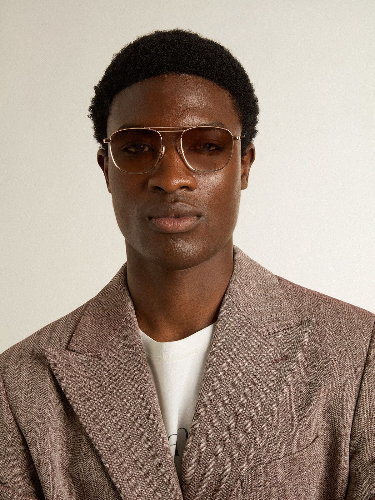 Aviator-style sunglasses with gold frame and beige lenses
